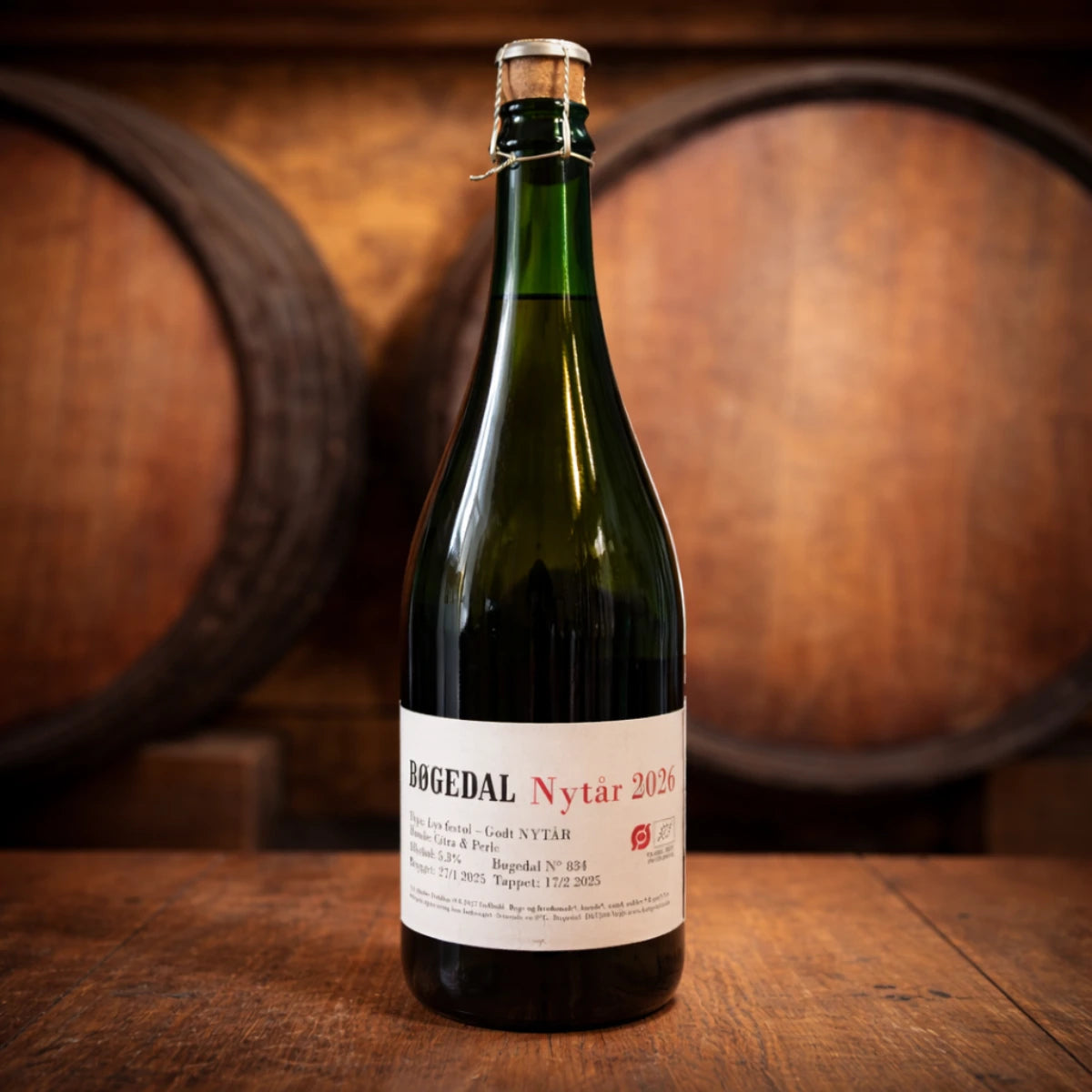 Flaske Bøgedal Nytår 2026 75 cl med korkprop og snøre – lys, elegant nytårsøl/festøl med florale noter af kaprifolie og magnoliablomst samt vilde forårsblomster, lang eftersmag af frugtig humle og sødme, mere syreholdig end bitter, brygget med økologisk malt, humle, sukker og gær; perfekt som aperitif og til skål kl. 24 samt salt og umami som lufttørret skinke, pølser og faste oste